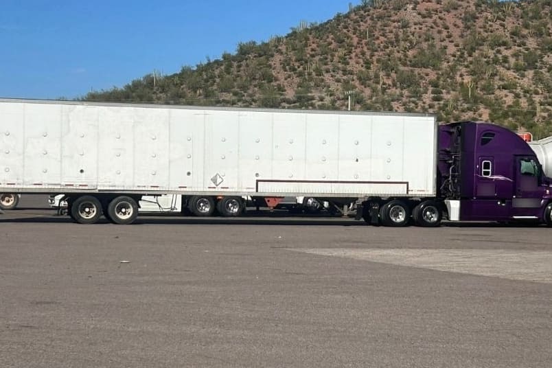 Tractocamión conectado a una caja seca blanca de 53 pies, estacionado en un patio junto a la carretera.